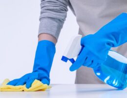 arms with rubber gloves on cleaning a table